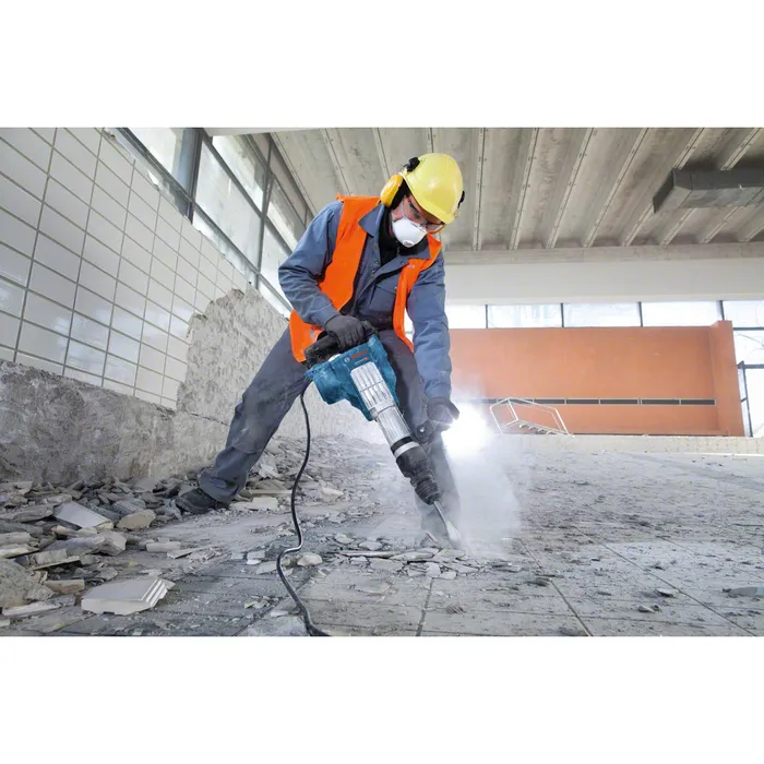 Demolición de un piso de cerámica con un martillo demoledor eléctrico aplicando supresión de polvo.