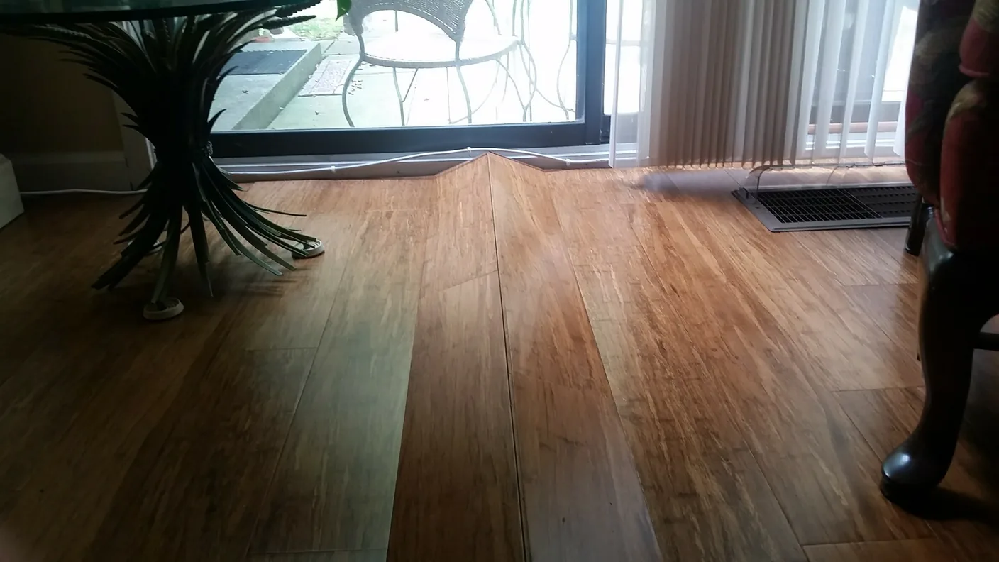 Piso laminado con peaking: una cresta donde dos tablas se levantan del subsuelo por exceso de presión lateral.