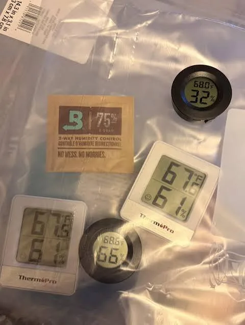 Termo-higrómetro digital junto a un paquete de calibración de dos vías dentro de una bolsa hermética para verificar su precisión.