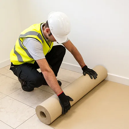 Protector de cartón transpirable cubriendo un piso recién instalado para protegerlo durante el resto de la obra.