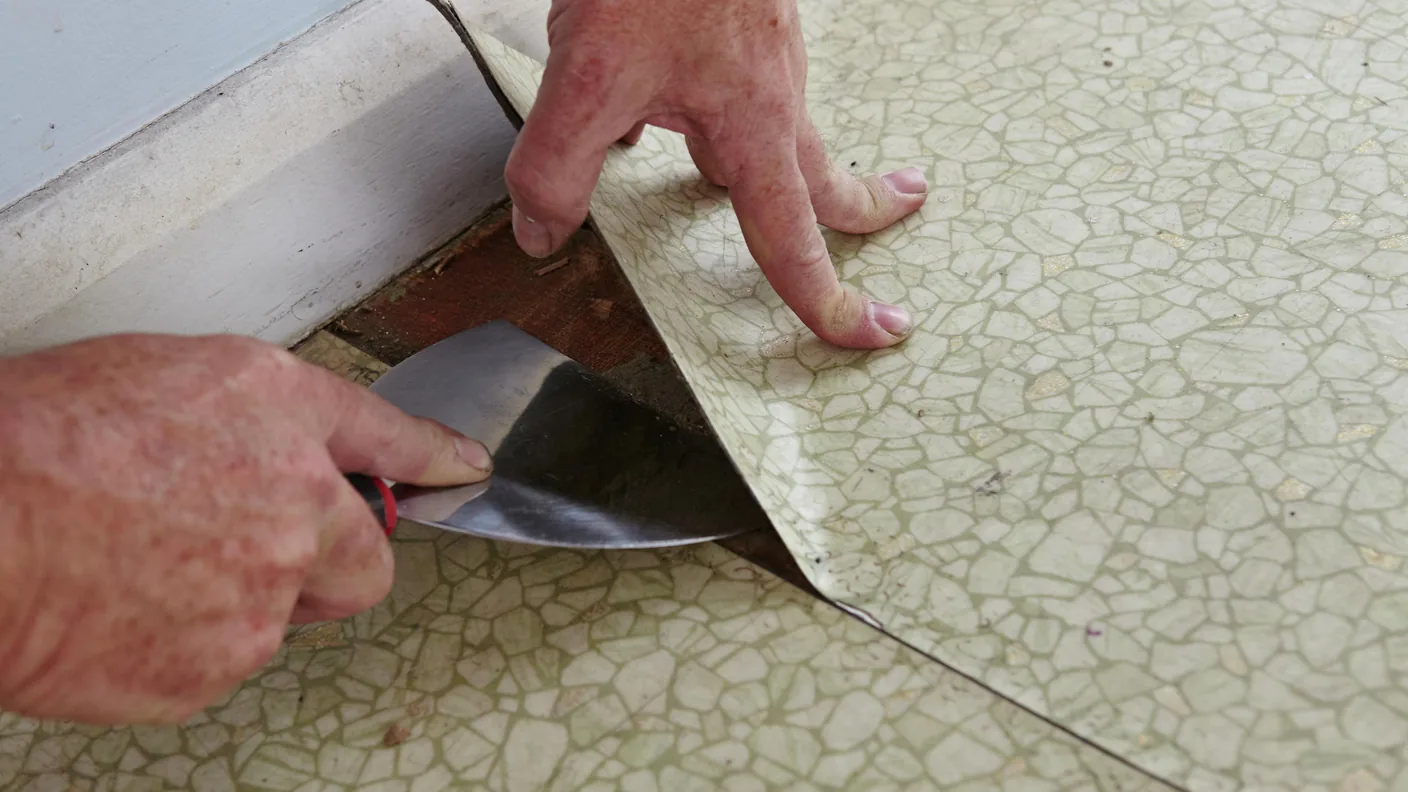 Remoción de una loseta de piso resiliente con un rascador de piso manteniendo el material en piezas íntegras.