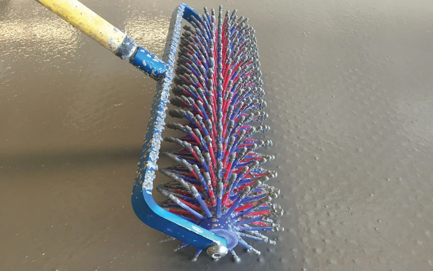 Rodillo de púas pasándose sobre mortero autonivelante fresco para liberar las burbujas de aire.